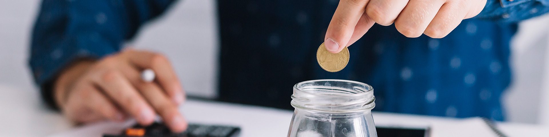 hand-putting-coin-jar-using-calculator